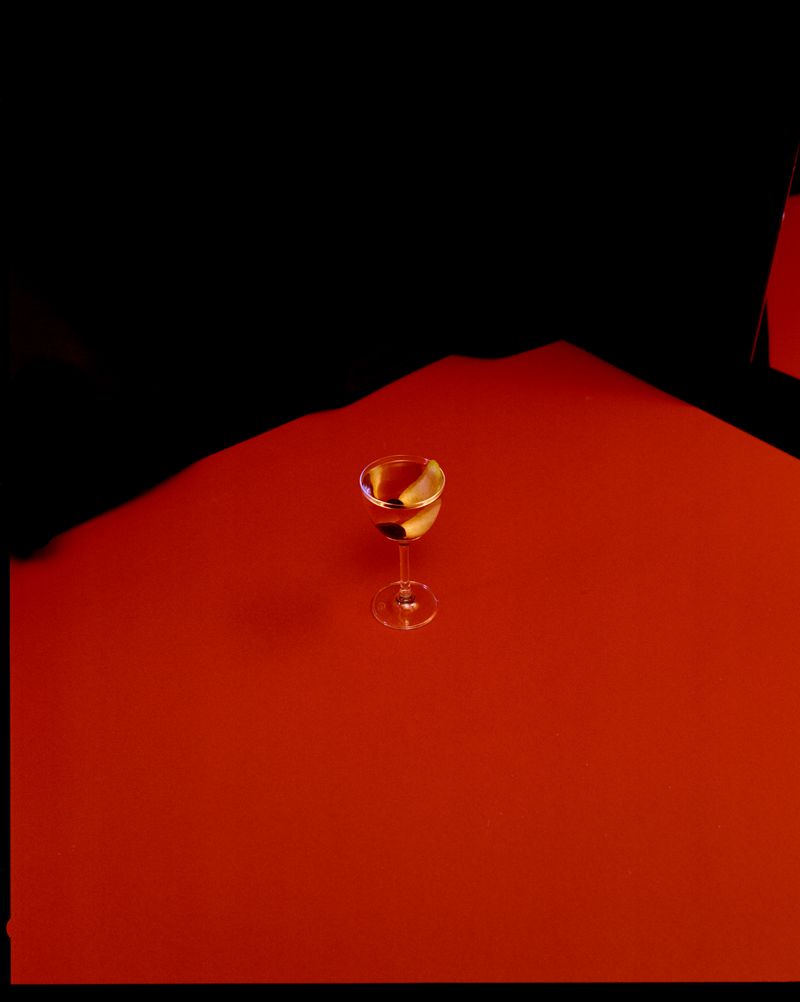 Single cocktail on red surface next to black velvet curtains