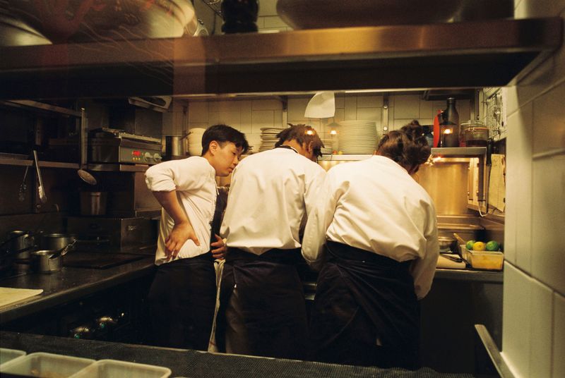 Three chefs huddled together in a restaurant kitchen
